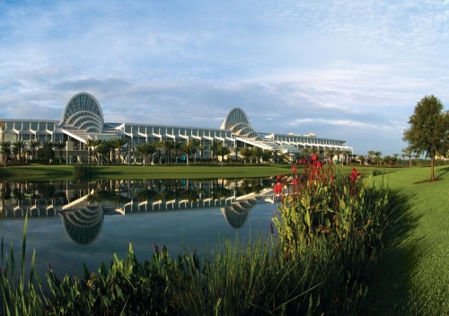 A pond surrounded by reeds and flowers with the Orange County Convention Center (OCCC) in the background.