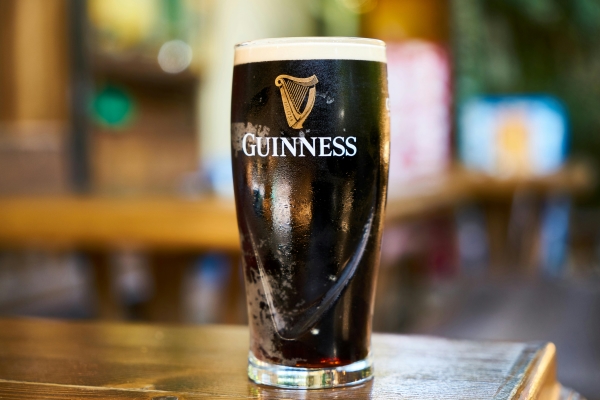 A pint glass of Guinness beer on a wooden pub table.