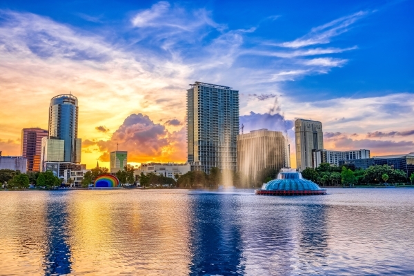 The skyline of downtown Orlando looking over Lake Eola and the Lake Eola Fountain at sunset. 